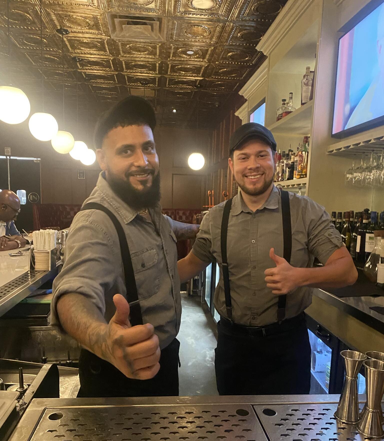 "AJ and Sam, bartending at Divieto in Aventura, FL, showcasing their skills while creating cocktails in a vibrant bar setting."