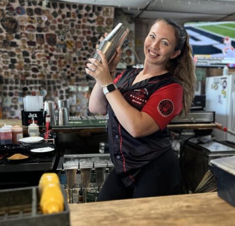 A bartender, Chelsea Miller, at Patches Pub in Panama City Beach, focused on mixing drinks behind the bar.