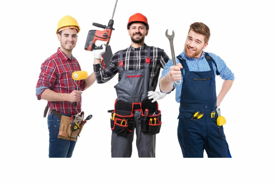 Drie mannen in bouwkleding, met verfroller, boormachine en moersleutel, dragen beschermende kleding voor werk in een lokale keukenwinkel.