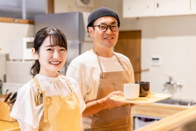 Two Asians standing in front of a coffee shop.