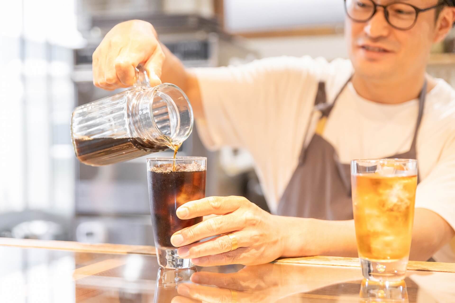 Bartender pouring iced coffee into a glass.
