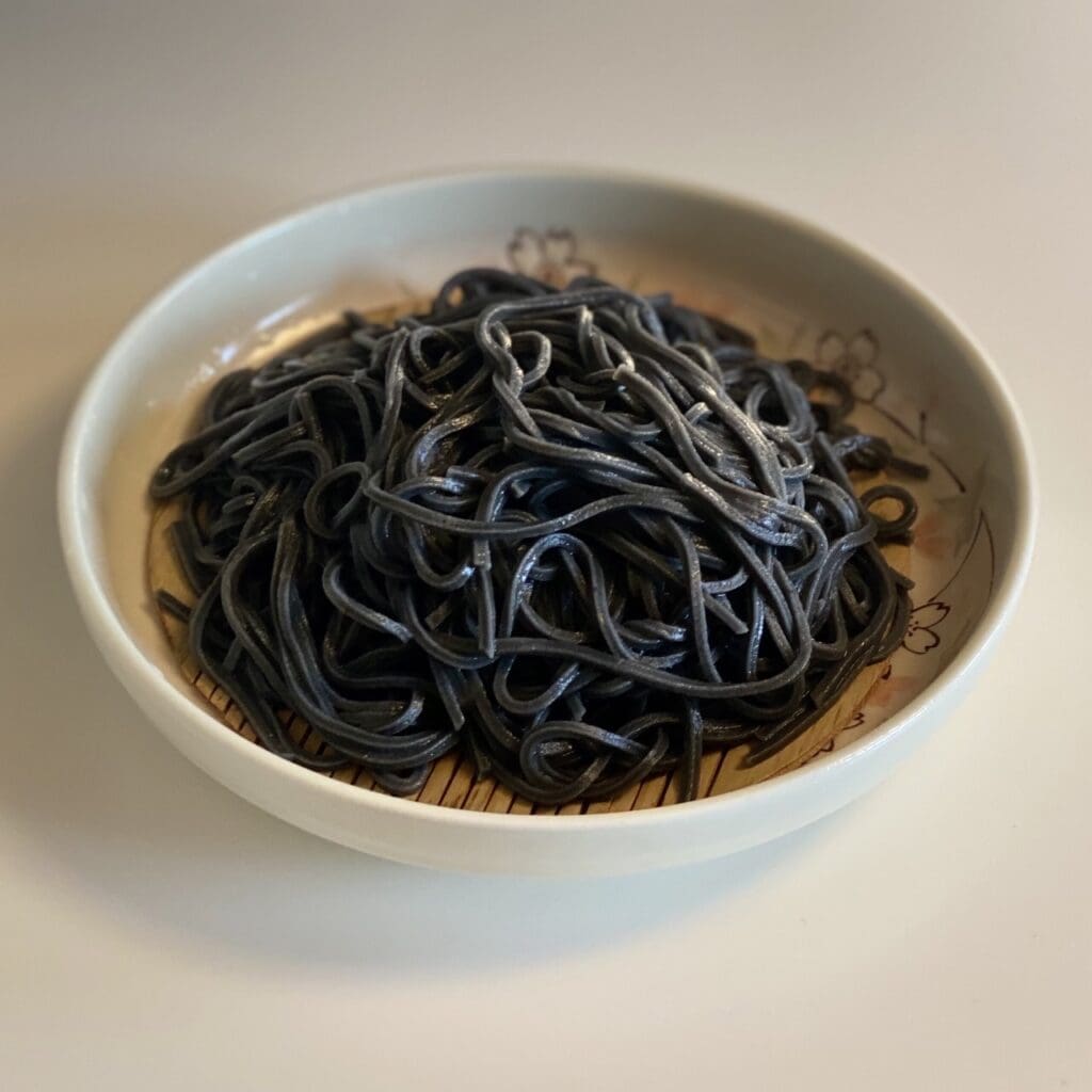 5 pieces of Kumiko brown rice daikoku noodles (okara, brown rice, hijiki & kelp, bamboo charcoal) (trial pack) are placed on the table.