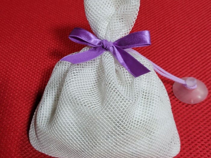 Cerâmica Antibacteriana para Banho Clean U Super Ribbon 230g ×2 unid. Cerâmica + turmalina (prata, zinco, cobre, zeólita de magnésio, etc.) É uma bolsa de malha branca com uma fita roxa.