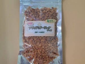 一袋格蘭諾拉麥片放在桌子上，裡面放著 2 × 150 毫升的 ajoen 大蒜油和大蒜片。