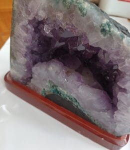 Một geode thạch anh tím may mắn lớn nằm trên một bệ gỗ nhỏ để thể hiện bên trong pha lê của nó.