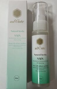 Флакон объемом 50 мл имеет маркировку «Adcute Essence Natural Herbal NMN» рядом с коробкой, которая рекламирует мононуклеотид никотинамида, питательную среду для стволовых клеток, экстракт среды для привыкания адипоцитов человека и увлажняющие свойства.