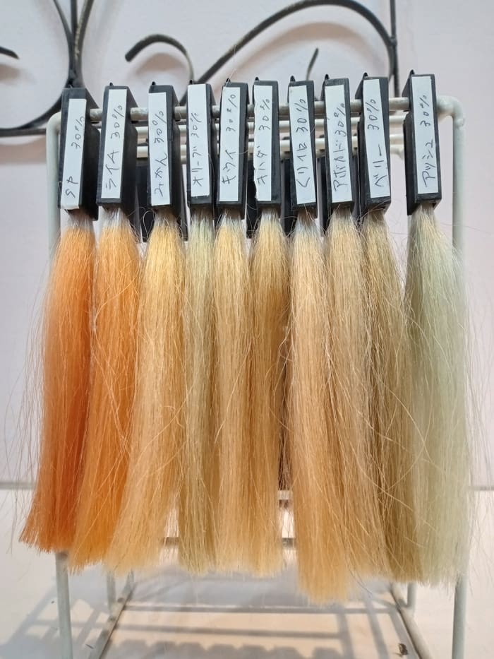 Set of hair color samples from orange to light blonde. Each comes with a handwritten note on a white tag, making it ideal for hair color enthusiasts looking for the perfect shade.
