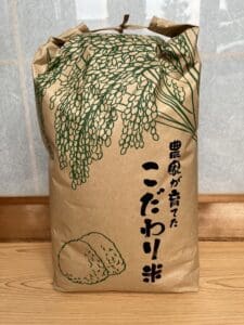 A brown paper bag containing specially cultivated rice with green illustrations and Japanese characters is placed on the tree.