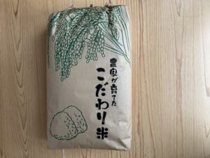 A brown paper bag of fresh white rice with an illustration of green rice and Japanese characters is placed on a tree.