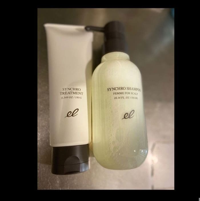 Dalawang mga produkto ng pag-aalaga ng buhok: isang tubo na may label na "Synchro Treatment" at isang bote ng bomba na may label na "Synchro Shampoo Femme for Scalp". Parehong nagtatampok ng isang minimalist na disenyo mula sa tatak ng ELECTRON.