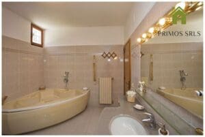 Bathrooms are outfitted with corner bathtubs, sinks and large mirrors. Tiled walls and floors add elegance, while decorative lighting above the mirrors adds charm. It has windows that let in natural light, making it the perfect retreat for a long weekend.
