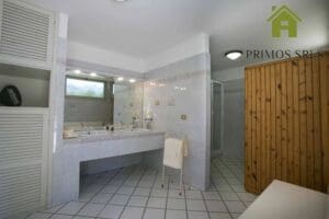 Bathroom with double sinks, large mirrors and tiled floors. The wooden partition on the right adds charm to the space, making it the perfect refreshing start to a long weekend.