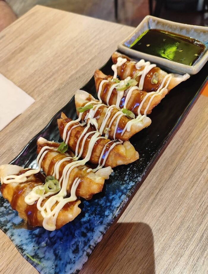Pour the sauce over 4 fried dumplings and serve them on a rectangular plate with green onions and serve with dipping sauce.