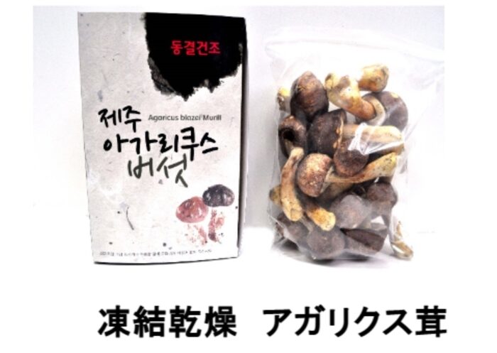 A box labeled "Agaricus Blazei Murill" in Korean sits next to a plastic bag containing freeze-dried agarisque mushrooms. The Japanese text can be found below.